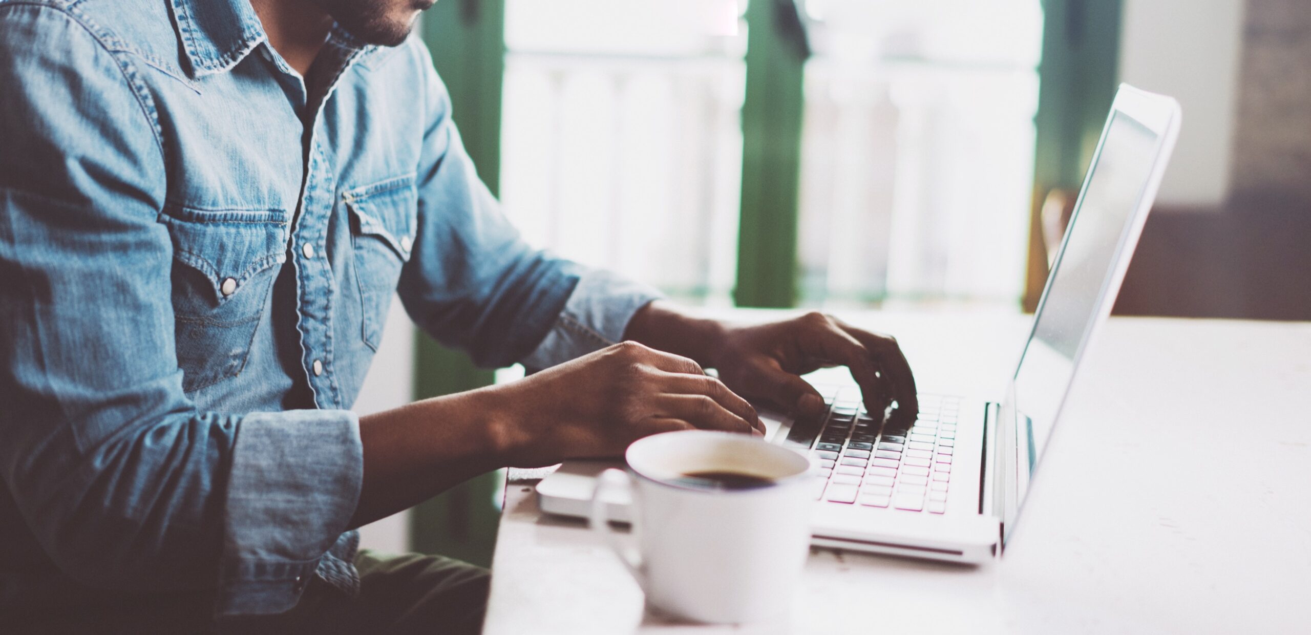 Man using laptop at home while sitting the wooden table.