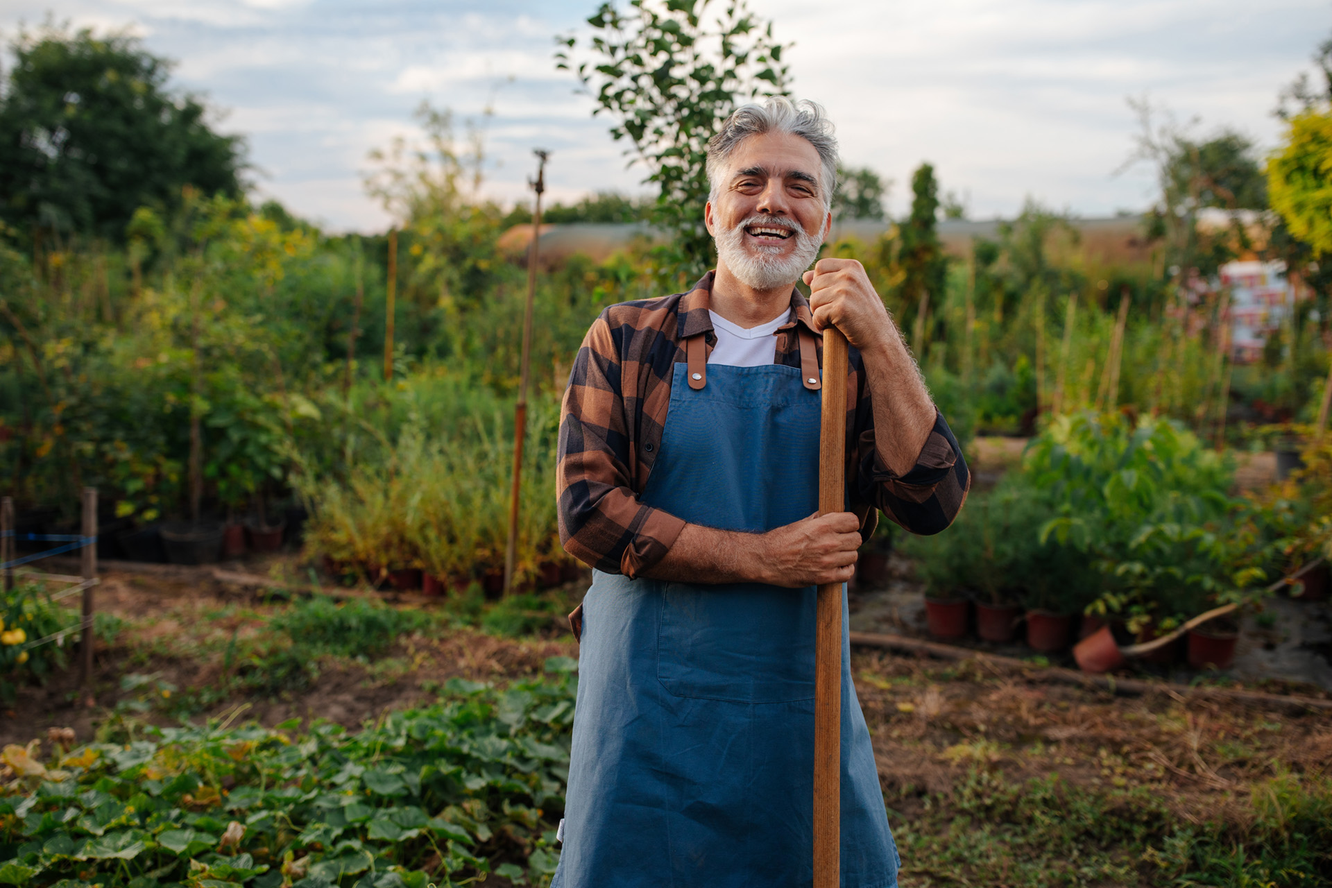 Man standing and holding a shovel in his garden